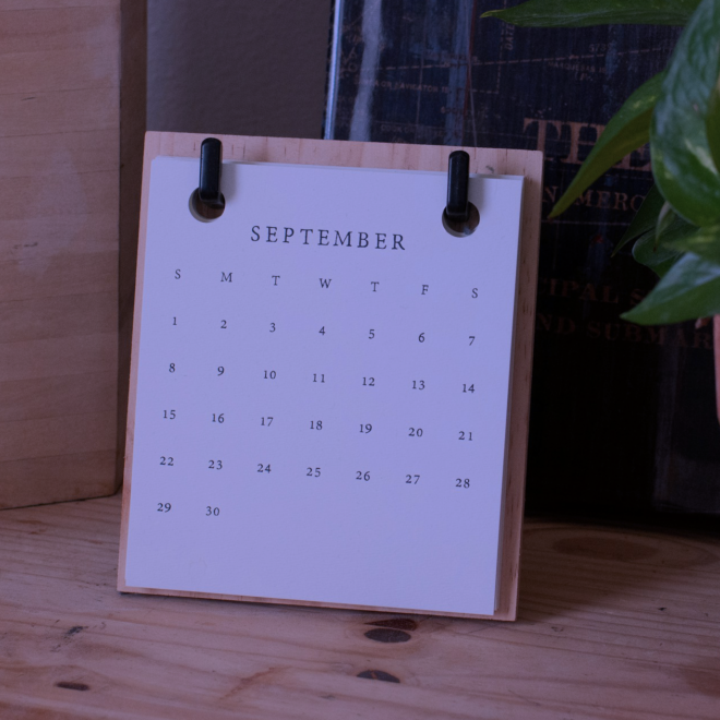 A imagem de um calendário de papel sobre uma mesa.