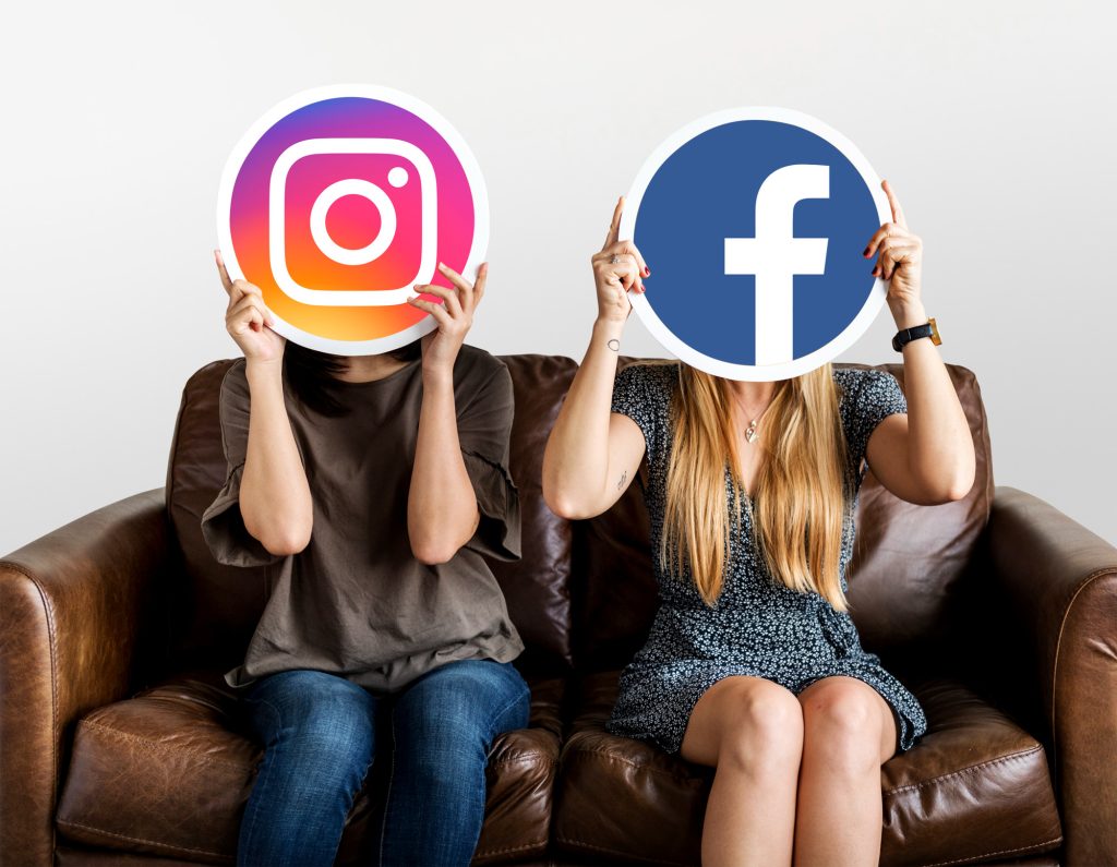 duas pessoas segurando os ícones do Instagram e do Facebook na frente de suas cabeças