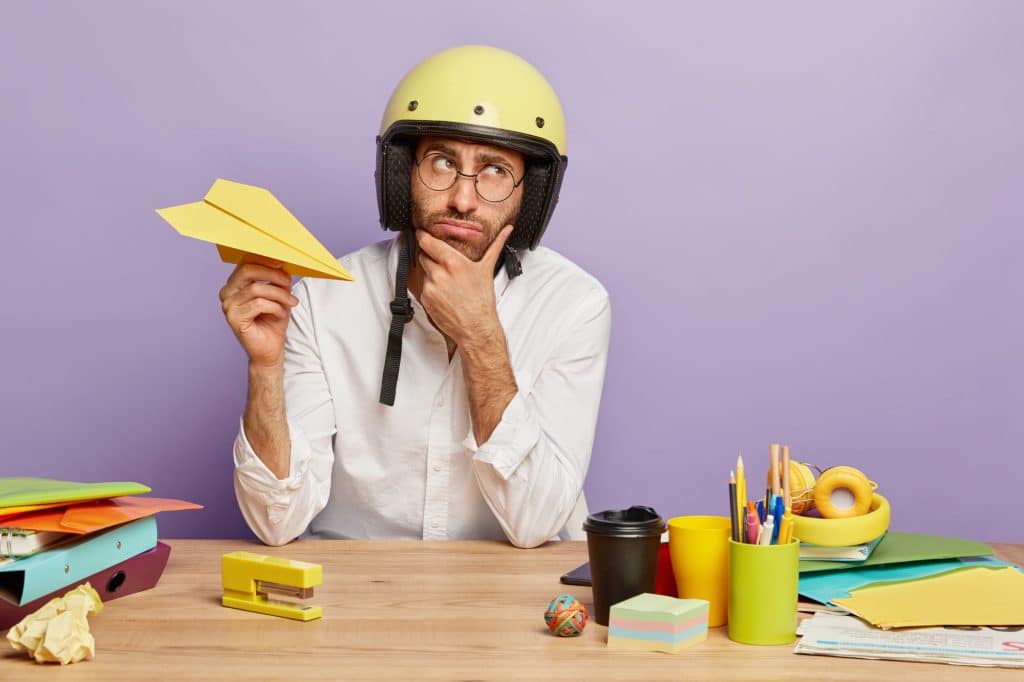 a person thinking with a helmet on their head and holding a paperplane