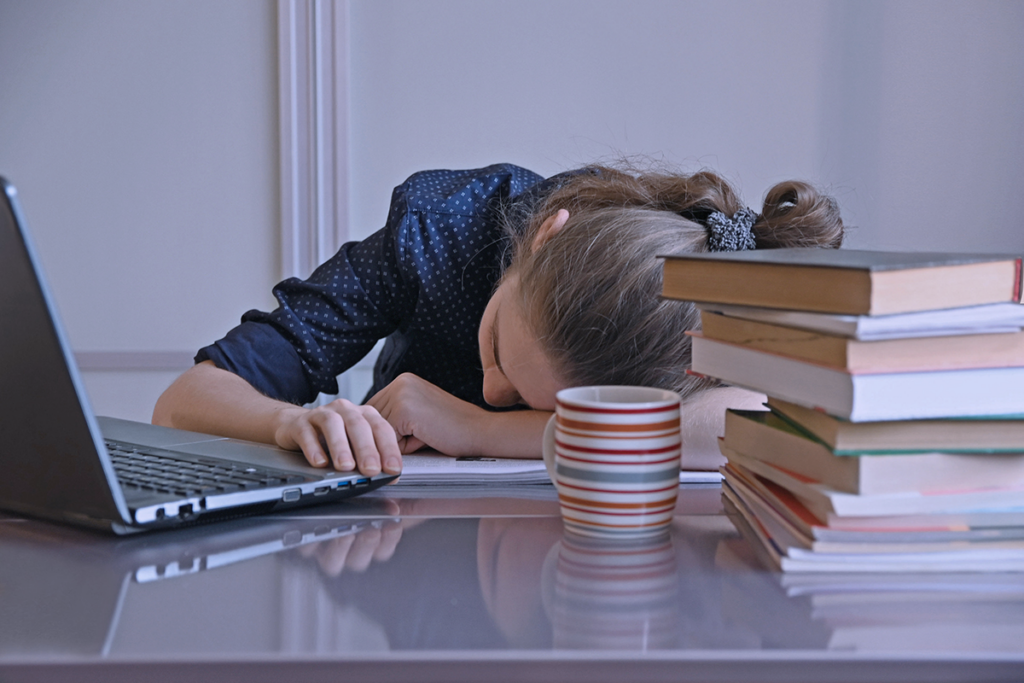 Mujer intentando estudiar, pero postergando las cosas.