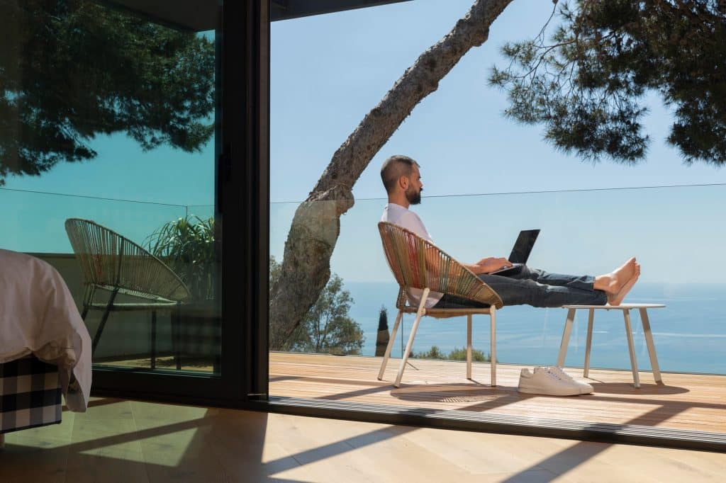 a man sitting on the terrace with a laptop facing the sea