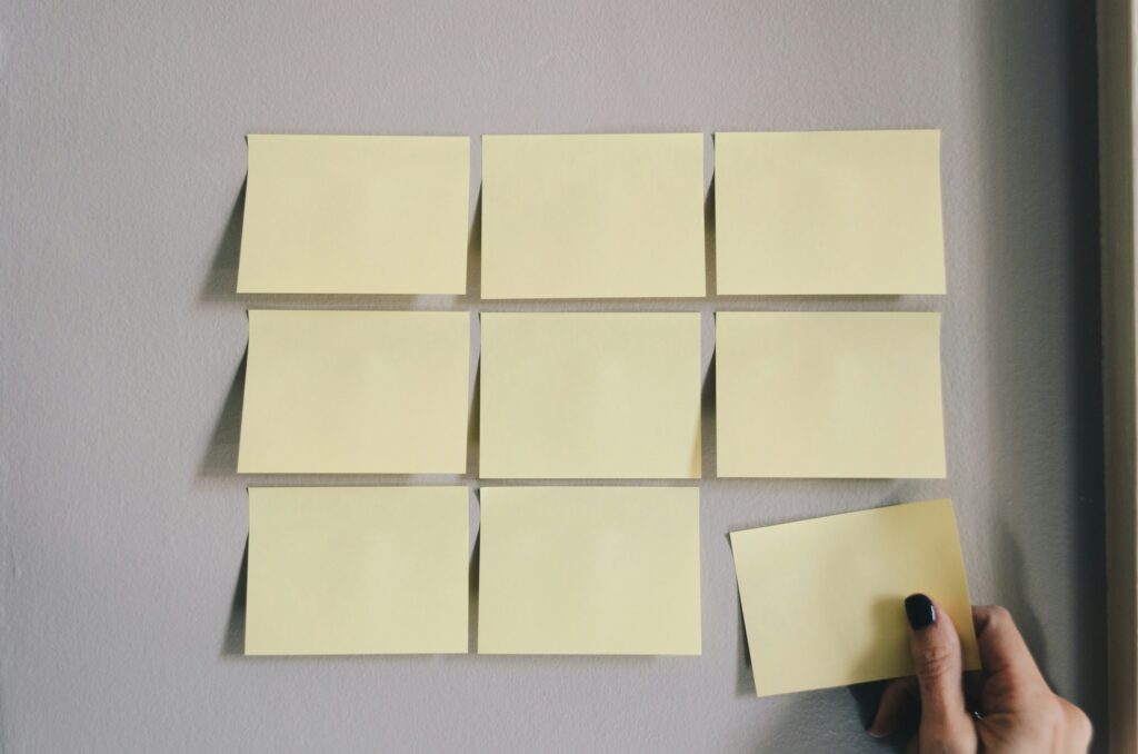 A grid of blank yellow post-it notes on a white wall.