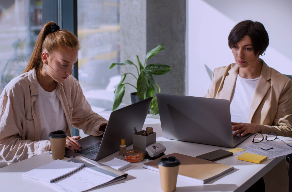 Two people working on their computers at a desk separately, symbolizing working in silos or the silo mentality on an individual scale