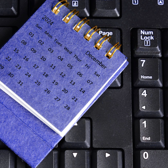 Um calendário roxo definido em um teclado preto do computador, simolizando o número de dias úteis médios em um mês.