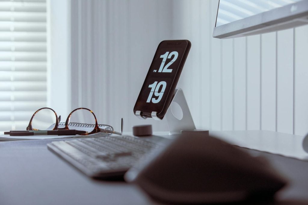 Minimalist workspace setup featuring clock display and keyboard.