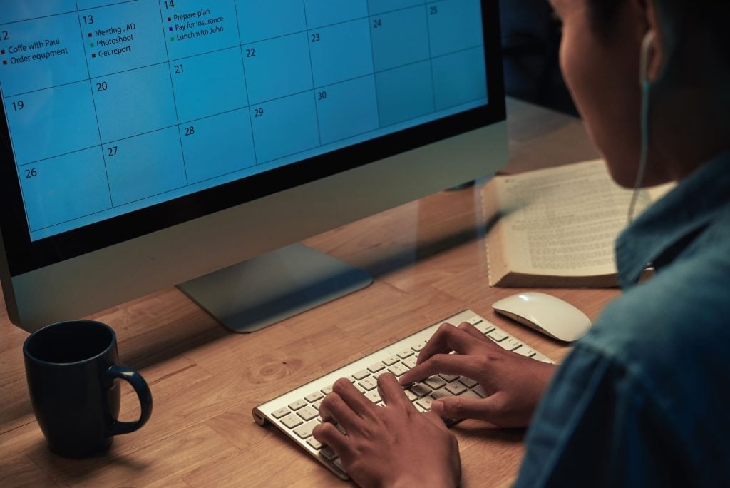 a person working on a computer and a calendar for a 4-day work week