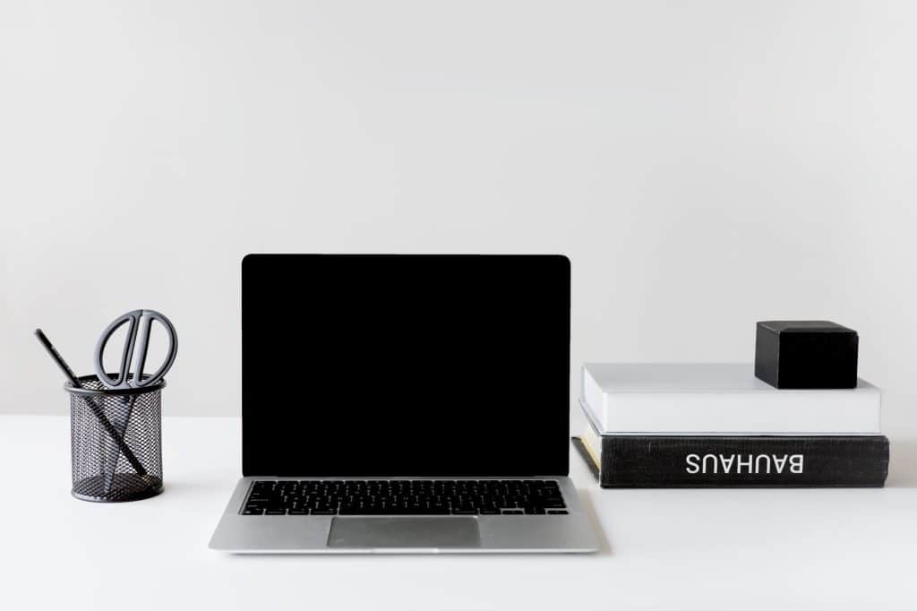 Clean and organized workspace featuring a laptop, books, and pen holder.