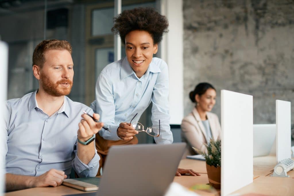 two colleagues looking at the laptop screen discussing activity level vs productivity